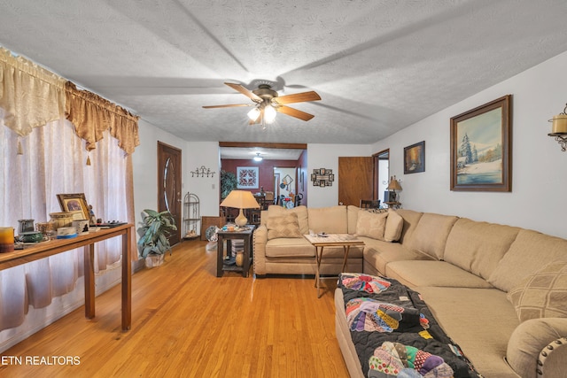 living room with a textured ceiling, hardwood / wood-style flooring, and ceiling fan