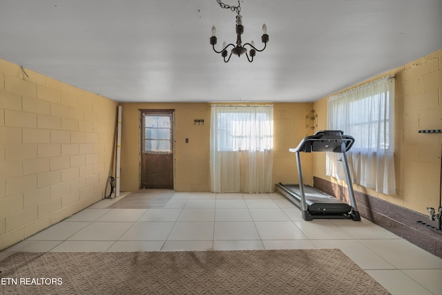 workout area with a chandelier and light tile patterned flooring