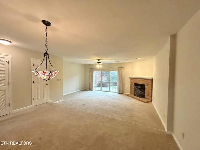 unfurnished living room featuring ceiling fan, a fireplace, and light carpet