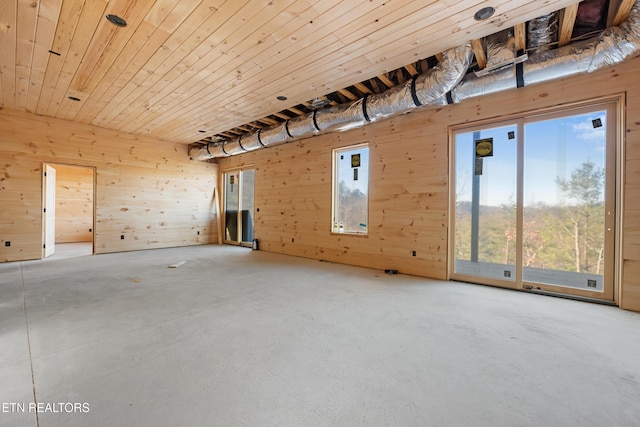 spare room with concrete floors, a healthy amount of sunlight, and wood walls