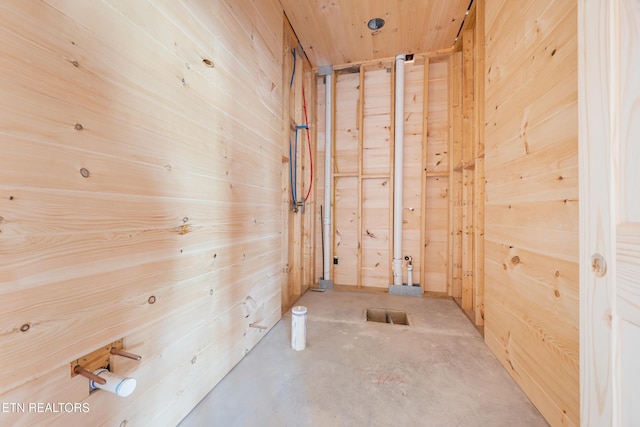 corridor with wood walls, wood ceiling, and concrete flooring