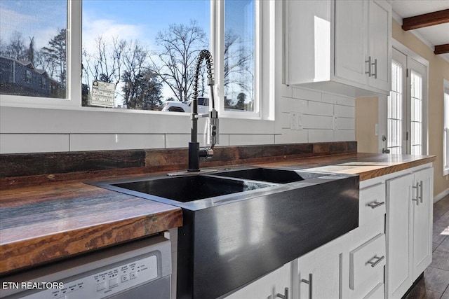 kitchen with wood counters, white dishwasher, sink, decorative backsplash, and white cabinetry