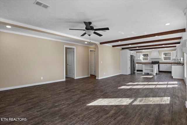 unfurnished living room with a textured ceiling, ceiling fan, sink, and dark wood-type flooring