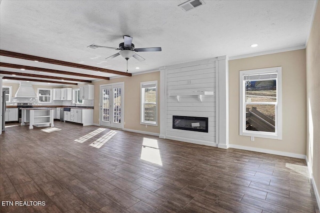 unfurnished living room featuring beamed ceiling, ceiling fan, a large fireplace, and a textured ceiling