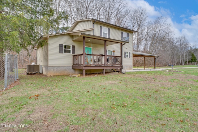 view of front of house featuring an attached carport, central AC, fence, and a front lawn