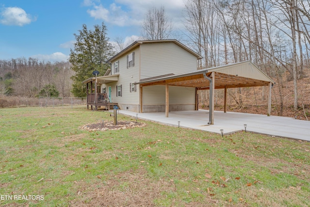 rear view of house featuring an attached carport, a yard, and driveway