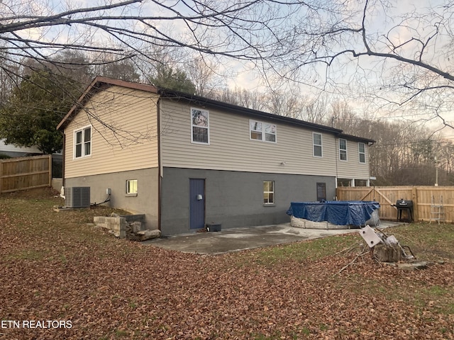 back of property with a covered pool, a patio area, and central air condition unit