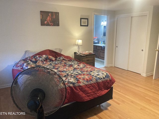 bedroom with ensuite bath, light hardwood / wood-style floors, and a closet