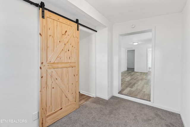 hall featuring a barn door and carpet floors