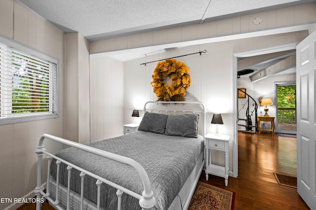 bedroom with dark hardwood / wood-style floors and a textured ceiling