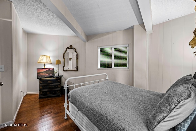 bedroom with beamed ceiling, dark hardwood / wood-style floors, and a textured ceiling