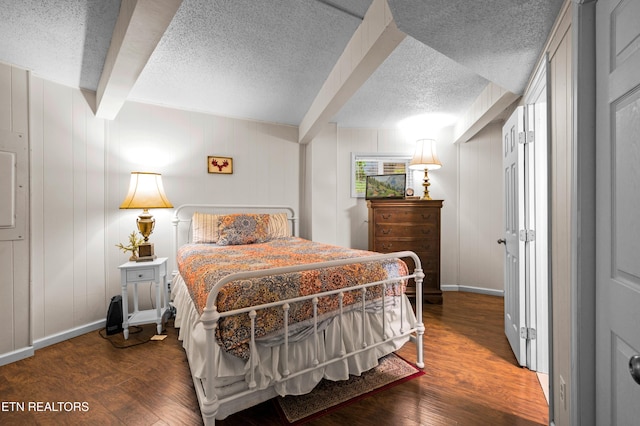 bedroom featuring beam ceiling, dark wood-type flooring, and a textured ceiling