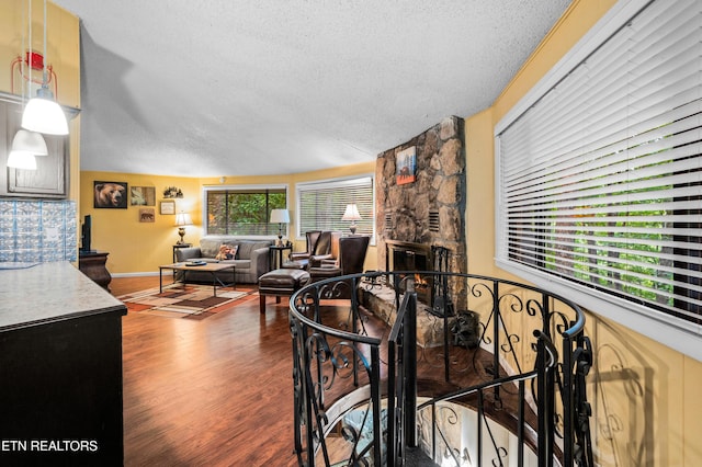 dining area featuring lofted ceiling, a stone fireplace, dark hardwood / wood-style floors, and a textured ceiling