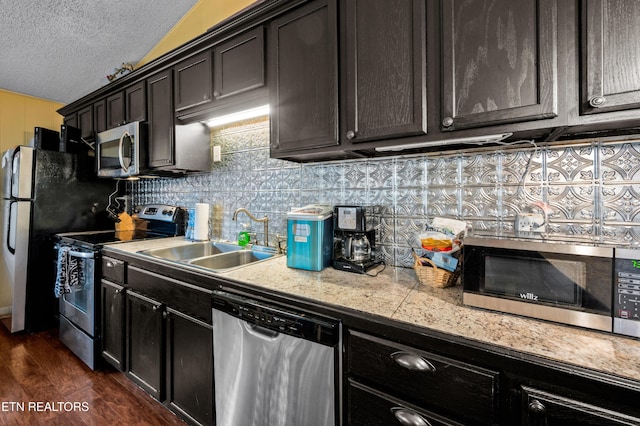 kitchen with tasteful backsplash, sink, dark hardwood / wood-style flooring, stainless steel appliances, and a textured ceiling