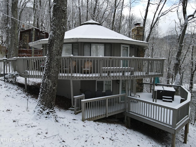 snow covered back of property featuring a wooden deck