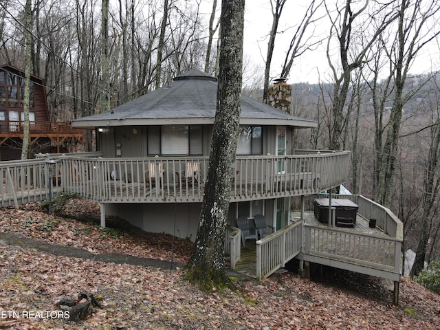 rear view of house with a hot tub and a wooden deck