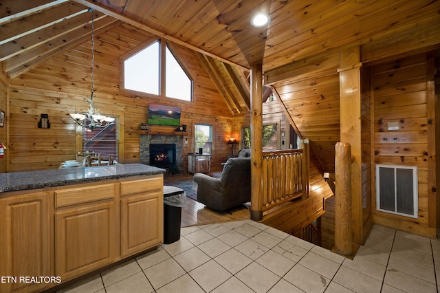 kitchen with wood walls, a stone fireplace, light tile patterned floors, and wooden ceiling