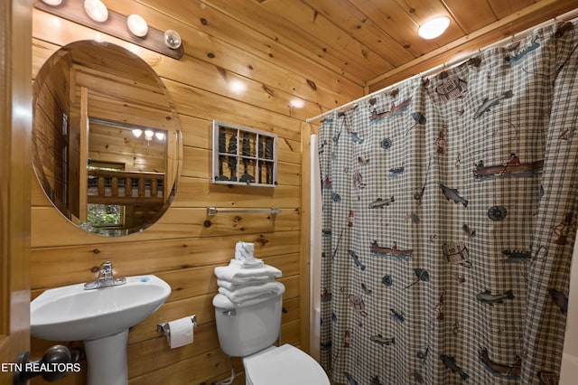 bathroom with wood ceiling, wooden walls, sink, toilet, and curtained shower