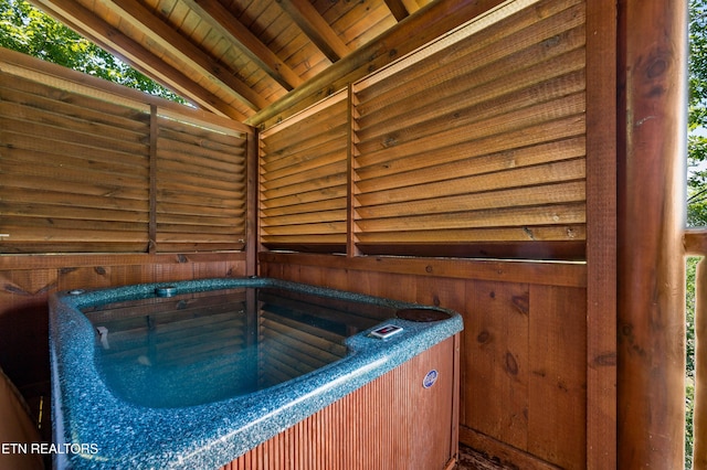 misc room featuring lofted ceiling with beams, wooden walls, and wood ceiling