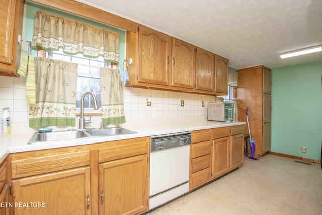 kitchen with white dishwasher, backsplash, sink, and a textured ceiling