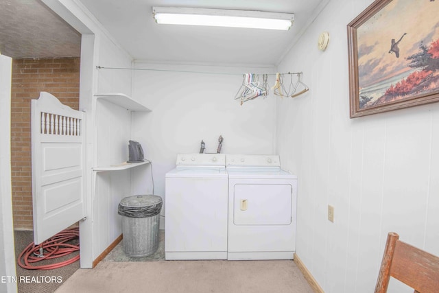 laundry room featuring crown molding, light colored carpet, washer and dryer, and brick wall