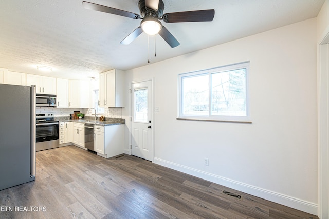 kitchen with sink, white cabinetry, light hardwood / wood-style floors, backsplash, and appliances with stainless steel finishes