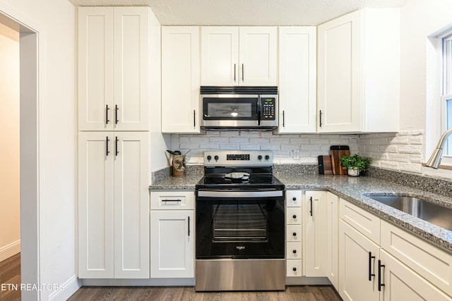 kitchen featuring sink, stainless steel appliances, white cabinetry, and dark stone countertops