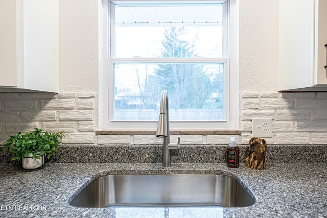 kitchen with sink, a healthy amount of sunlight, dark stone countertops, and tasteful backsplash