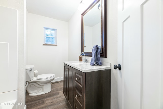 bathroom with toilet, vanity, and hardwood / wood-style floors