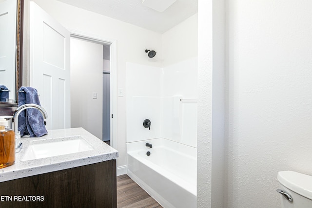 full bathroom with toilet, washtub / shower combination, vanity, and hardwood / wood-style floors