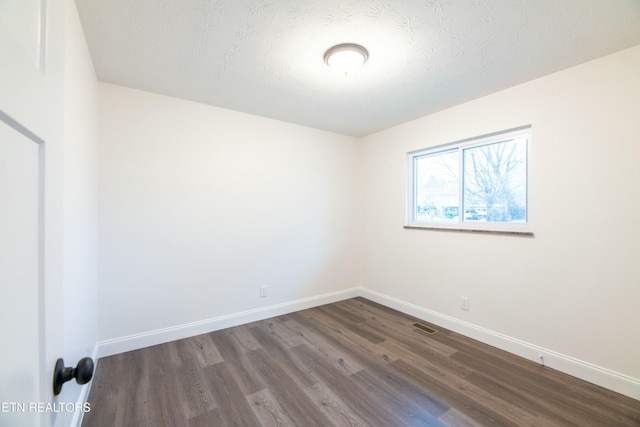 empty room featuring dark wood-type flooring and a textured ceiling