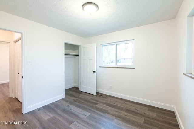 unfurnished bedroom featuring a textured ceiling, a closet, and dark hardwood / wood-style flooring