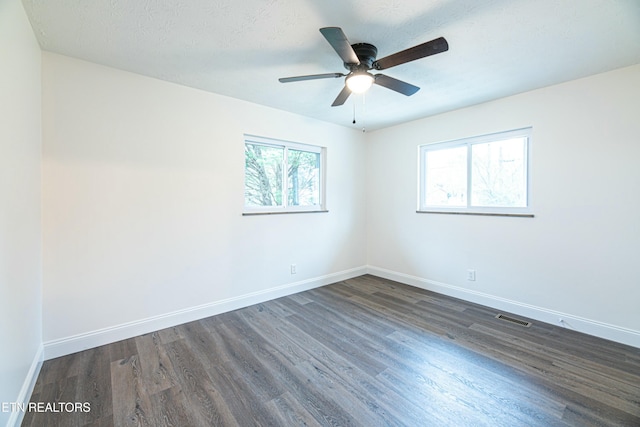 spare room with a healthy amount of sunlight, ceiling fan, a textured ceiling, and dark hardwood / wood-style floors