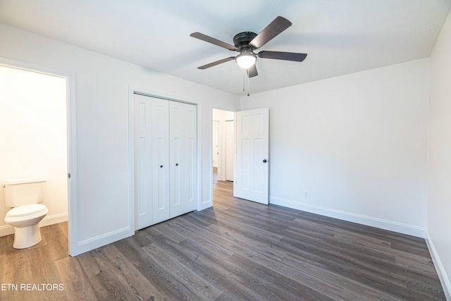 unfurnished bedroom featuring dark hardwood / wood-style flooring, a closet, ceiling fan, and ensuite bath