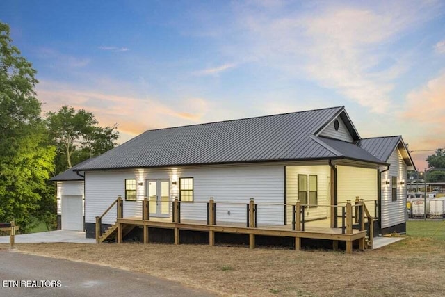 back house at dusk featuring a garage and french doors