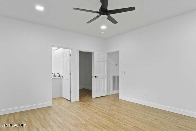 unfurnished bedroom featuring a walk in closet, ceiling fan, and light hardwood / wood-style floors