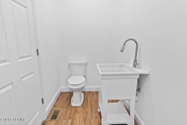 bathroom with toilet, wood-type flooring, and sink