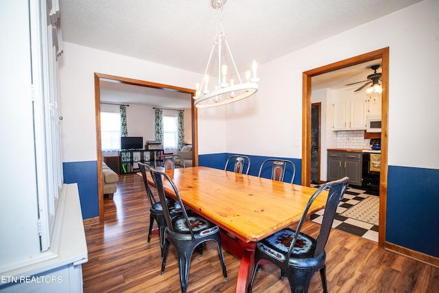 dining space with ceiling fan with notable chandelier, dark hardwood / wood-style floors, and a textured ceiling