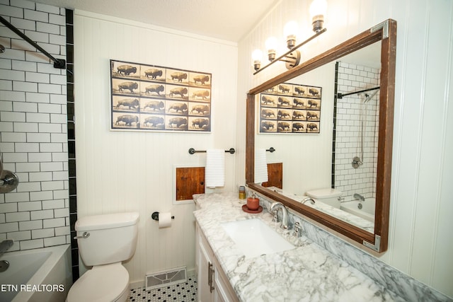 full bathroom with tiled shower / bath, wood walls, vanity, toilet, and a textured ceiling