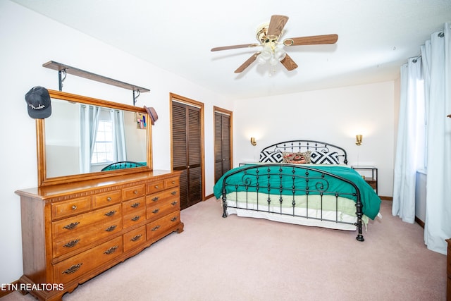 carpeted bedroom featuring two closets and ceiling fan