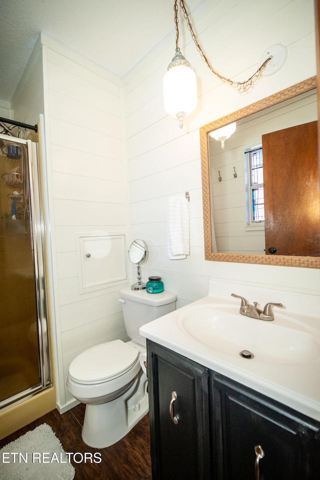 bathroom featuring vanity, wood-type flooring, a shower with shower door, and toilet