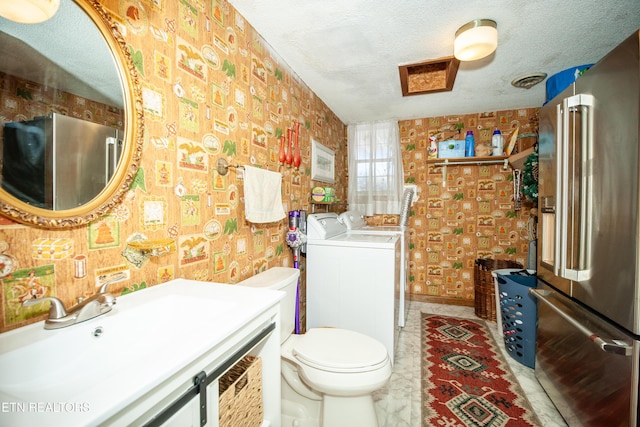 bathroom featuring vanity, washer and dryer, a textured ceiling, and toilet