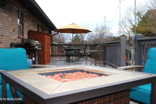 wooden terrace with area for grilling and an outdoor fire pit