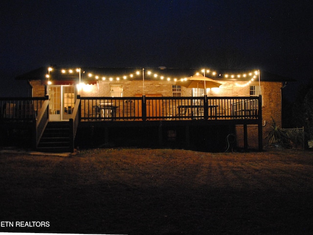 back house at night featuring a wooden deck