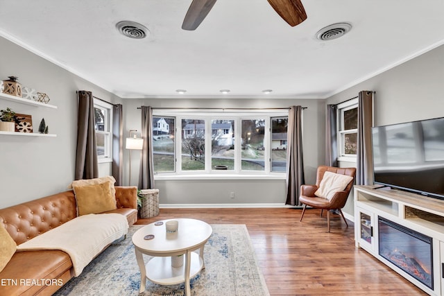 living room with wood-type flooring, ceiling fan, and crown molding