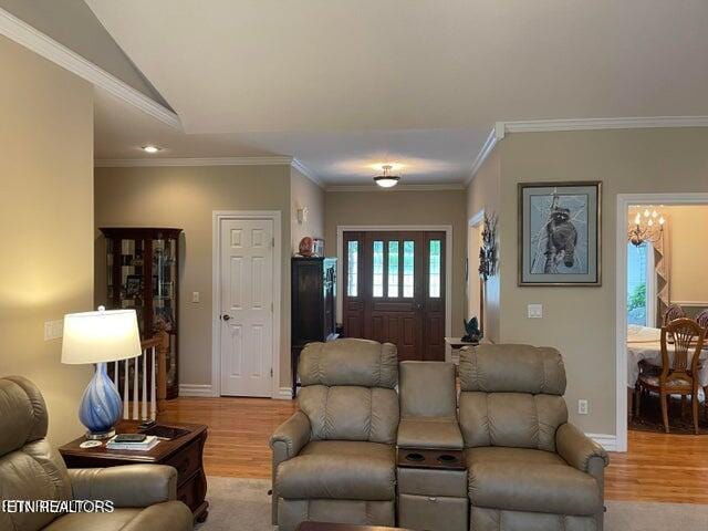 living area featuring lofted ceiling, ornamental molding, light wood-type flooring, and baseboards