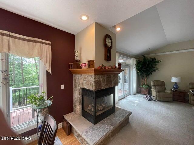 sitting room featuring lofted ceiling and a stone fireplace