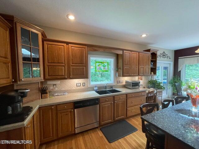 kitchen with a sink, light wood-style flooring, decorative backsplash, and stainless steel dishwasher