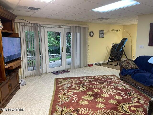 living room with baseboards, light colored carpet, a drop ceiling, and french doors