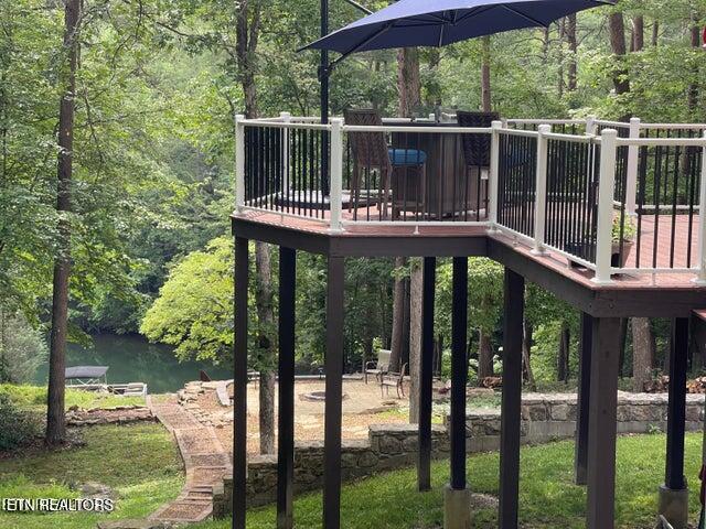 view of jungle gym with a patio area, a forest view, and a deck with water view